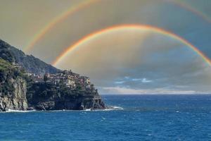 manarola cinque terre pittoresk dorp met dubbele regenboog lucht achtergrond foto