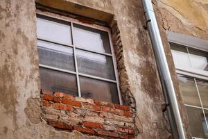 oud vuil houten venster en rood steen met gips muur in oud stad- in Europa foto