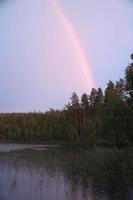 regenboog weerspiegeld in de meer wanneer het regent. in de achtergrond Woud foto