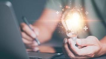 idee inspiratie combineert creativiteit, innovatie en op het randje technologie voor oplossen toekomst bedrijf problemen. ,zakenman Holding een licht lamp, tonen een plus teken Aan de tafel foto