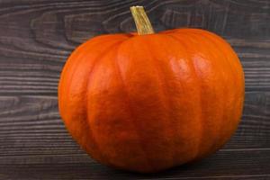 oranje pompoen met een stang, detailopname Aan een plank, houten achtergrond. herfst achtergrond. kopiëren ruimte. foto