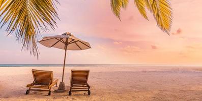 prachtige panoramische natuur. tropisch strand zonsondergang als zomer eiland landschap met stoelen paraplu palmbladeren kalme kust, kust. luxe reizen panoramische bestemmingsbanner voor vakantie of vakantie foto