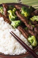 rundvlees met broccoli en rijst macro, eetstokjes. verticaal bovenaanzicht foto