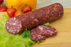 salami Aan houten bord en houten achtergrond foto