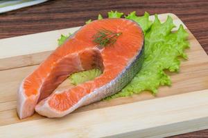 rauw Zalm steak Aan houten bord en houten achtergrond foto