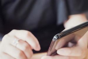 vrouw met diamanten ring bij de hand met smartphone in café-restaurant foto