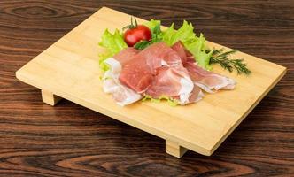 prosciutto Aan houten bord en houten achtergrond foto