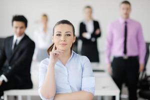 bedrijf vrouw staand met haar personeel in achtergrond foto