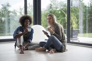 multi-etnisch Dames zitten Aan de verdieping en drinken koffie foto