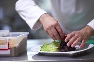 chef in hotel keuken voorbereidingen treffen en decoreren voedsel foto