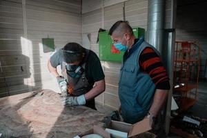 industrieel werk gedurende een pandemie. twee mannen werk in een zwaar metaal fabriek, vervelend een masker Aan hun gezicht ten gevolge naar een coronavirus pandemisch foto