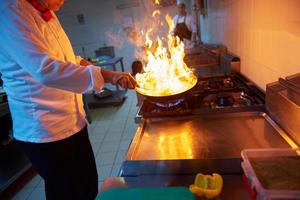 chef in hotel keuken bereiden voedsel met brand foto