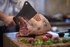 chef snijdend groot stuk van rundvlees foto