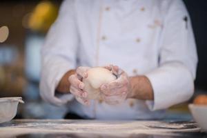 chef handen voorbereidingen treffen deeg voor pizza foto