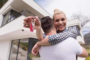 paar knuffelen in voorkant van nieuw luxe huis foto