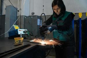 een vrouw werken in de modern metaal productie en verwerken industrie lassen de Product en bereidt zich voor het voor een cnc machine foto