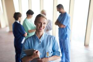 vrouw dokter met tablet computer staand in voorkant van team foto