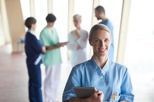 vrouw dokter met tablet computer staand in voorkant van team foto