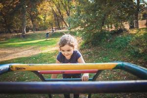 gelukkig klein meisje spelen Aan de speelplaats Bij de park. foto