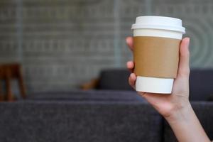 vrouw hand- Holding bruin papier kop van heet drinken in koffie cafe. nemen weg heet drinken beker. foto