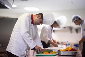 chef in hotel keuken plak groenten met mes foto