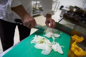 chef in hotel keuken plak groenten met mes foto