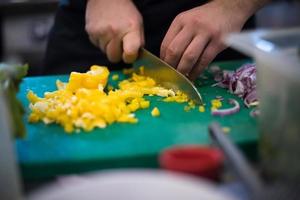 chef-kok handen snijden verse en heerlijke groenten foto