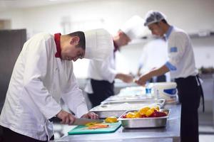 chef in hotel keuken plak groenten met mes foto