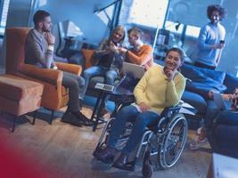 portret van gehandicapt zakenvrouw in een rolstoel in voorkant van haar verschillend bedrijf team Bij kantoor foto