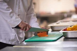 chef in hotel keuken plak groenten met mes foto