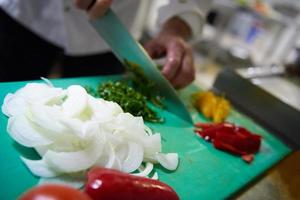 chef in hotel keuken plak groenten met mes foto