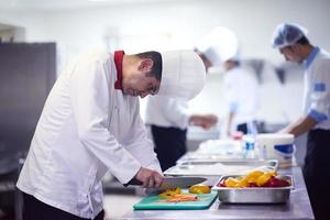 chef in hotel keuken plak groenten met mes foto