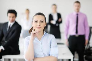 bedrijf vrouw staand met haar personeel in achtergrond foto