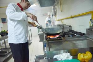 chef in hotel keuken bereiden voedsel met brand foto