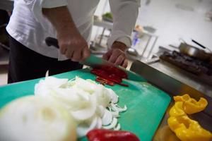 chef in hotel keuken plak groenten met mes foto