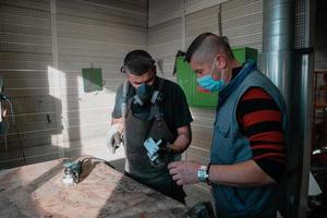 industrieel werk gedurende een pandemie. twee mannen werk in een zwaar metaal fabriek, vervelend een masker Aan hun gezicht ten gevolge naar een coronavirus pandemisch foto