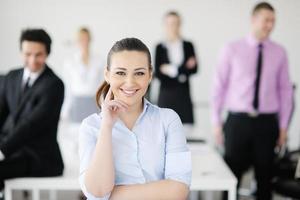 bedrijf vrouw staand met haar personeel in achtergrond foto