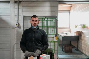 een Mens werken in een fabriek, vervelend een gezicht masker en handschoenen, werken gedurende een coronavirus pandemisch foto