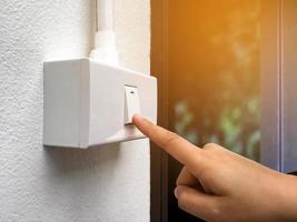 menselijk vinger Aan de schakelaar Aan en schakelaar uit paneel, concept voor beurt uit de elektrisch lamp na gebruik makend van het , voordat gaan uit en naar opslaan onze planeet en globaal opwarming, zacht en selectief focus. foto