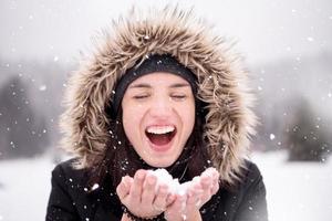 jong vrouw blazen sneeuw Aan besneeuwd dag foto