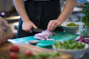 chef handen snijdend de ui met mes foto