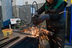 een vrouw werken in de modern metaal productie en verwerken industrie lassen de Product en bereidt zich voor het voor een cnc machine foto