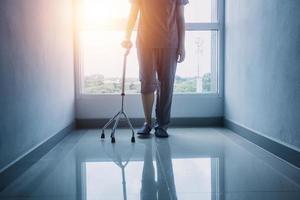 jong Aziatisch fysiek therapeut werken met senior vrouw Aan wandelen met een wandelaar foto