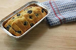 bosbes muffin taart in brood pan Aan houten tafelblad met servet foto