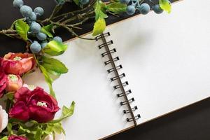 schetsboek met kleurrijk boeket en bosbes Aan zwart bord achtergrond in vlak leggen ontwerp. foto