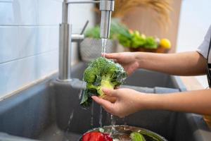 mensen het wassen groenten in de keuken. foto