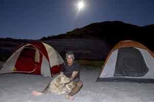 Mens en hond Bij tent kamp Bij nacht in de woestijn foto