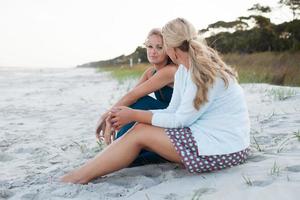 twee vrouwen zitten praten op het strand