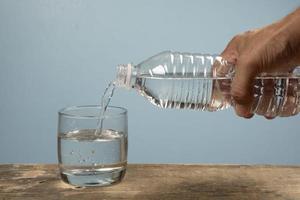 persoon vulling een kop van water met huisdier fles foto