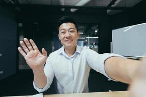 Aziatisch zakenman werken in modern kantoor, geslaagd Mens pratend Aan video telefoon telefoontje foto